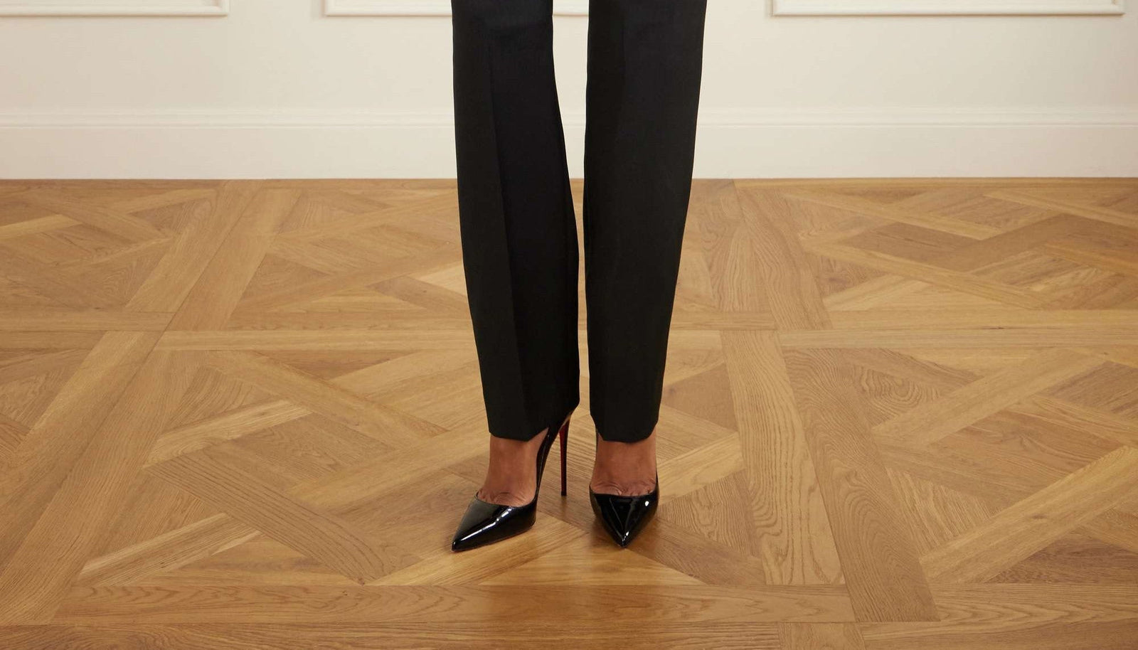 Christian Louboutin So Kate 120 in black patent leather, worn with tailored trousers, the signature red sole visible